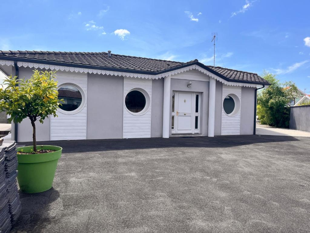 アンデルノ・レ・バンにあるvilla patio proche centre villeの2つの窓と鉢植えの木がある白いガレージ