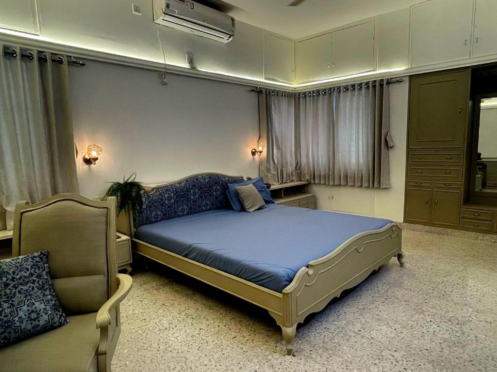 a bedroom with a large bed and a chair at La Shangrila Charming City Center Villa in Ahmedabad
