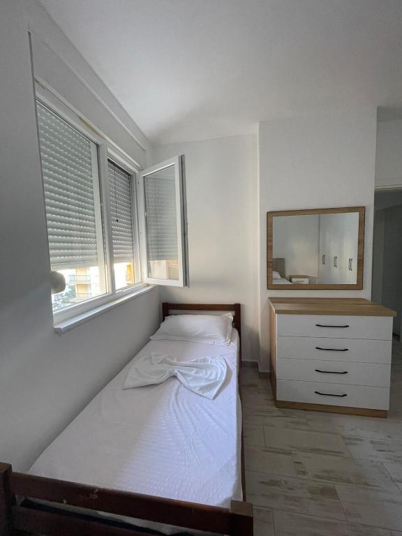 a bedroom with a bed and a dresser and windows at Il Sol Apartment in Lezhë
