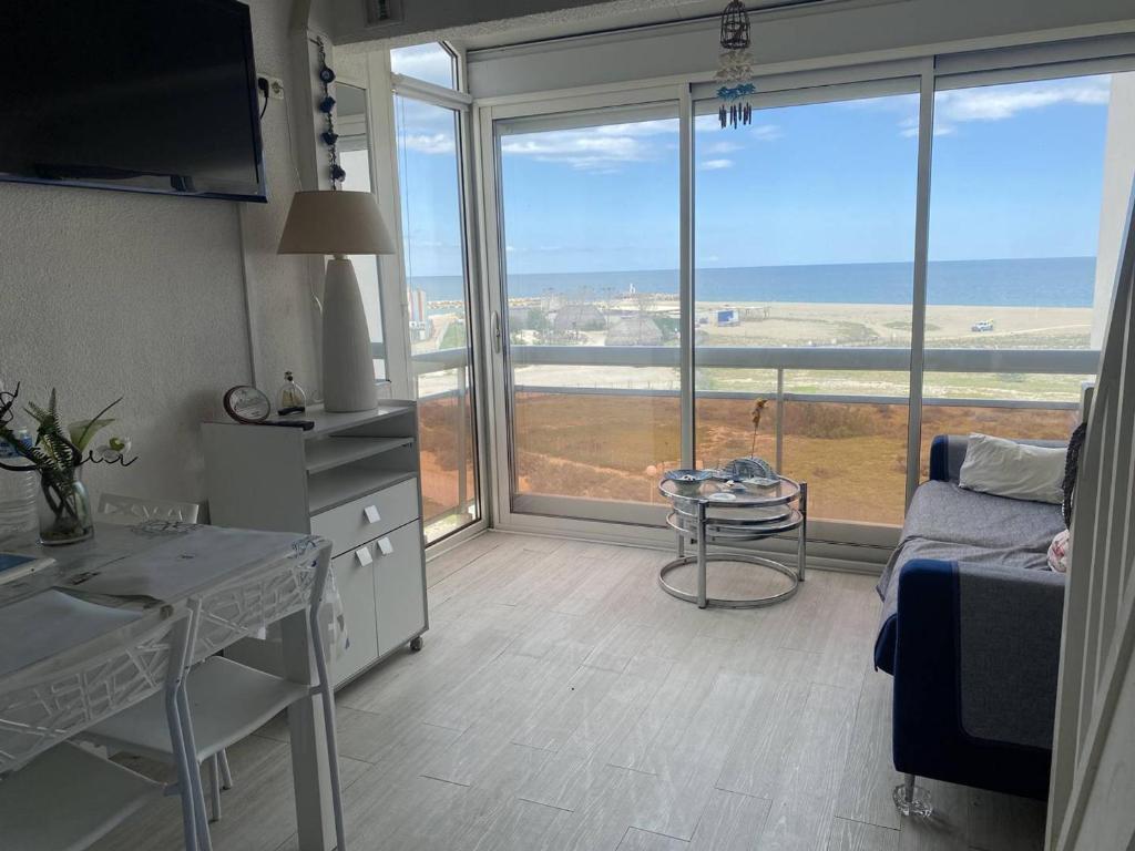 un salon avec une table et une grande fenêtre dans l'établissement Duplex à 30m de la plage avec parking privé - FR-1-782-63, au Barcarès