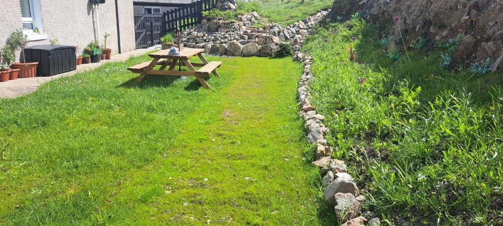 a wooden picnic table sitting in the grass at Cliff Cottage in Valtos