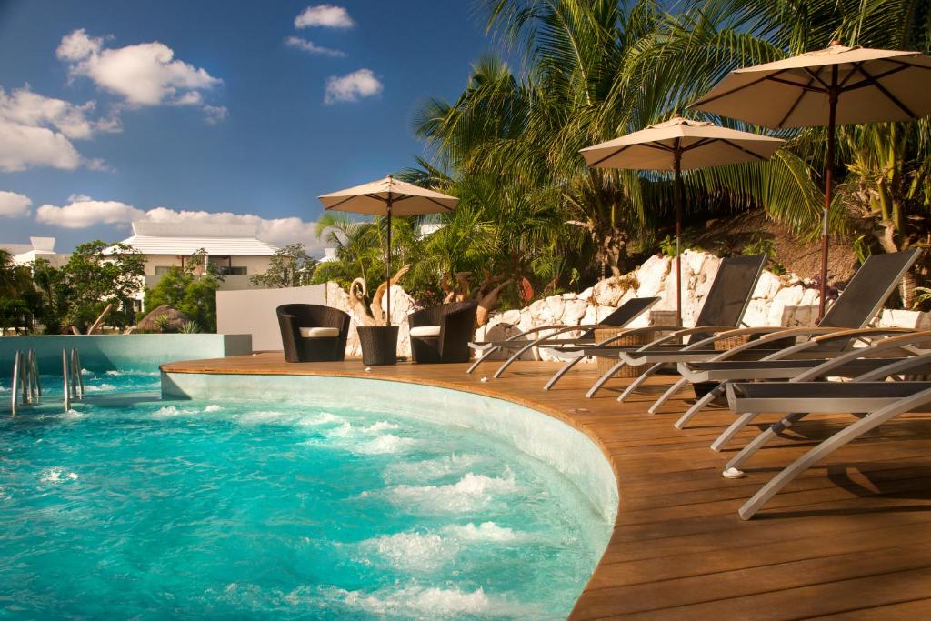una piscina con sillas y sombrillas en una terraza de madera en Select Club at Sandos Caracol All Inclusive - Adults Only Area, en Playa del Carmen