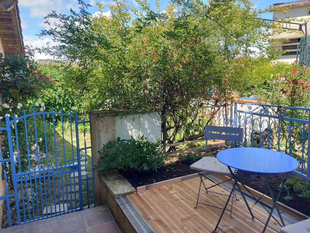 a wooden deck with a table and a blue fence at STUDIO LA ROSERAIE avec jardin privatif proche centre ville in Moissac