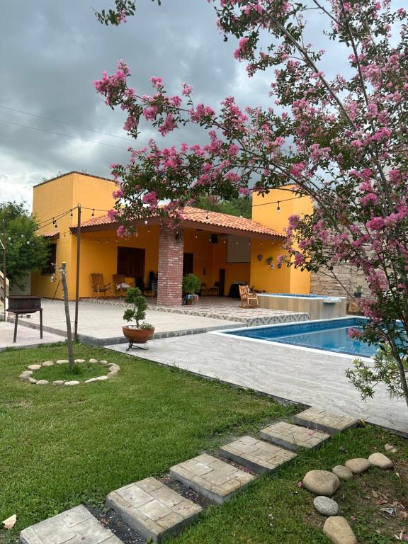 a house with a swimming pool and a tree with pink flowers at Casa Villa Antigua in Montemorelos