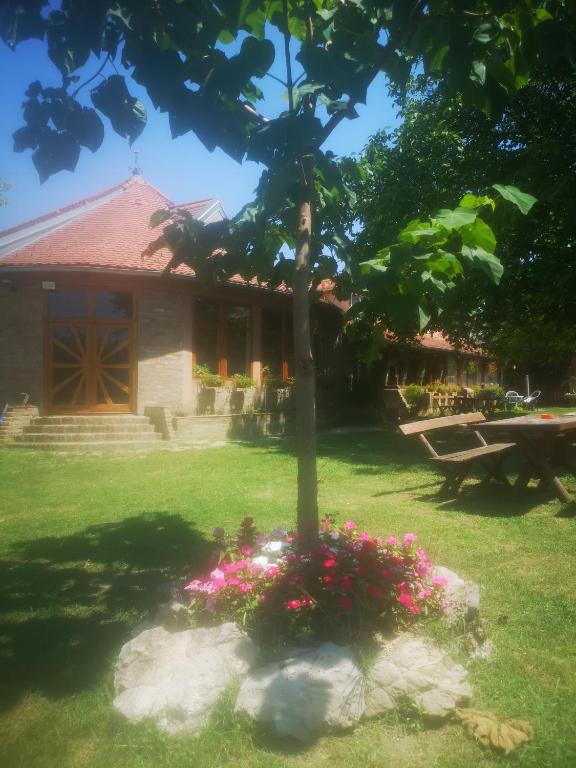 a house with a tree in a yard with flowers at CycloCamp & Hostel in Skorenovac