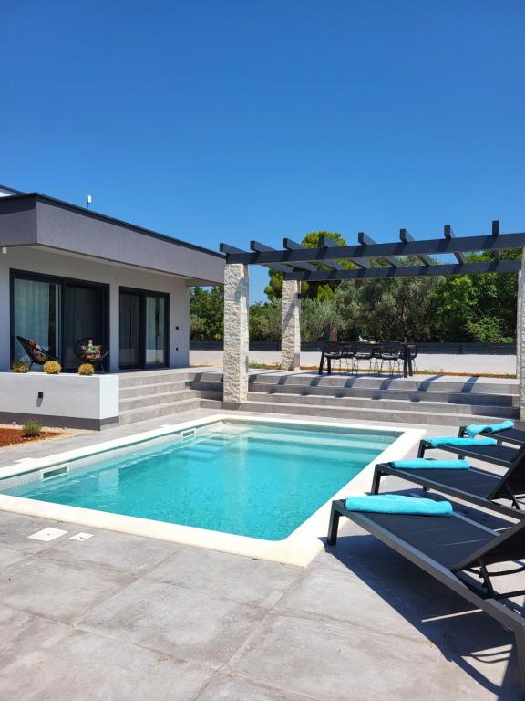 a swimming pool with lounge chairs next to a house at Villa Bucko - Fazana in Fažana