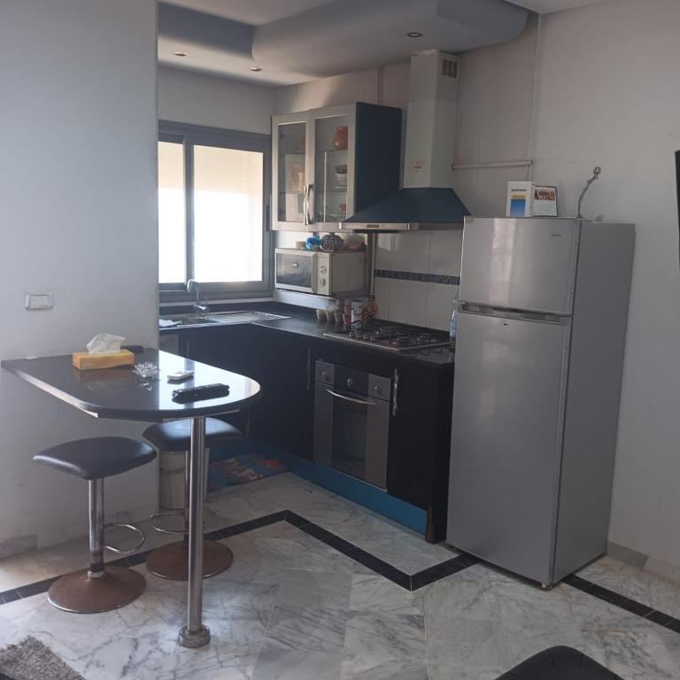 Il comprend une cuisine équipée d'un réfrigérateur et d'une table. dans l'établissement S1 Chat Mariem Vue Mer, à Hammam Sousse