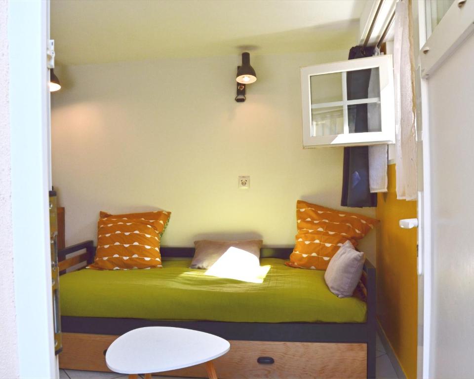 a small room with a green bed with pillows at L'atelier de Papy d'Albi - Parking - Centre Albi accessible à pied in Albi