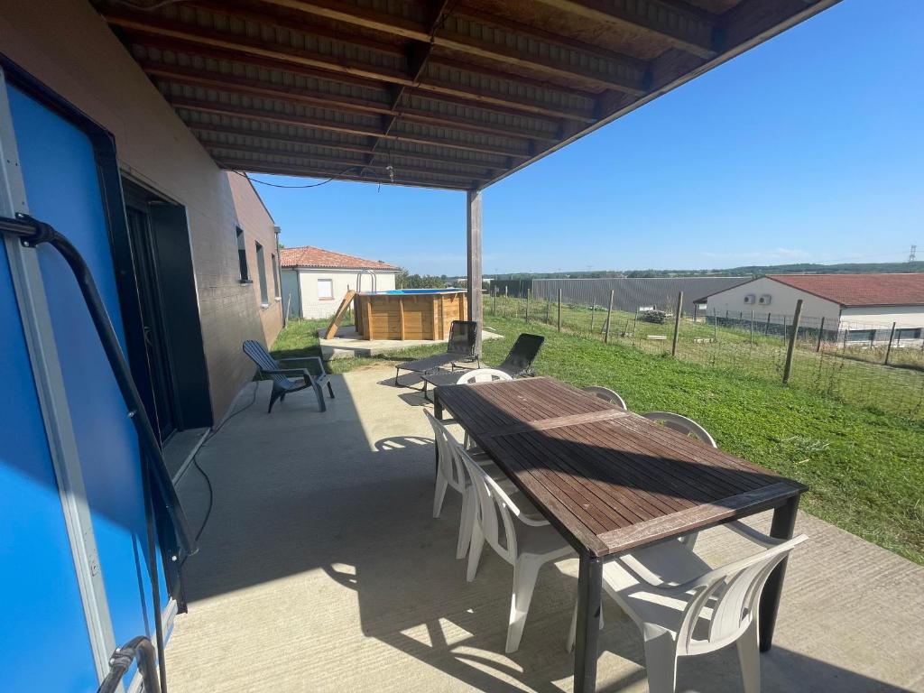 une terrasse avec une table et des chaises en bois. dans l'établissement Maison 10 personnes, à Gragnague