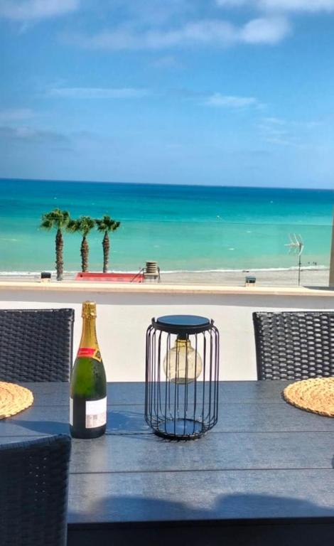 a table with a bottle of wine on a table with the beach at Apartamento Sunshine Grao in Burriana