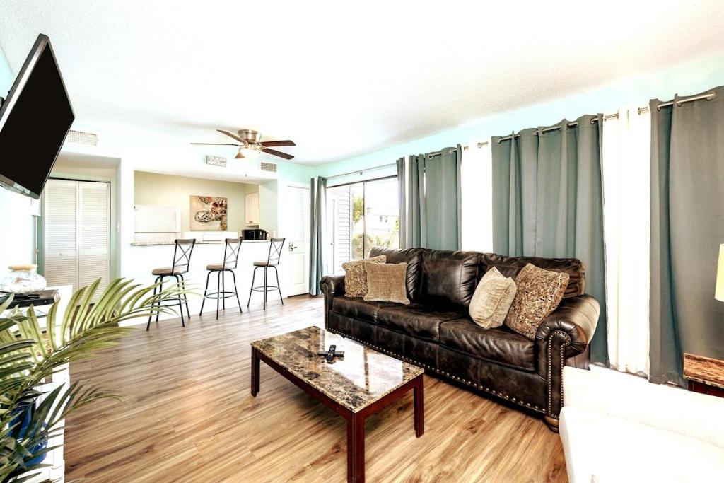 a living room with a leather couch and a table at Kings Cove Central Destin 3 Community Pools in Destin