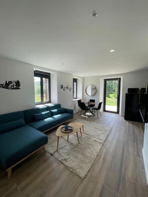 un salon avec un canapé bleu et une table dans l'établissement Le petit jurassien 2, à Bellefontaine