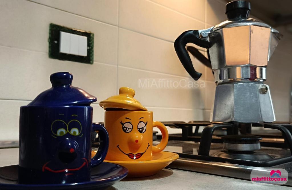 two coffee cups sitting on a counter next to a coffee maker at Bilocale Moka a Melzo vicino alla stazione e al centro in Melzo