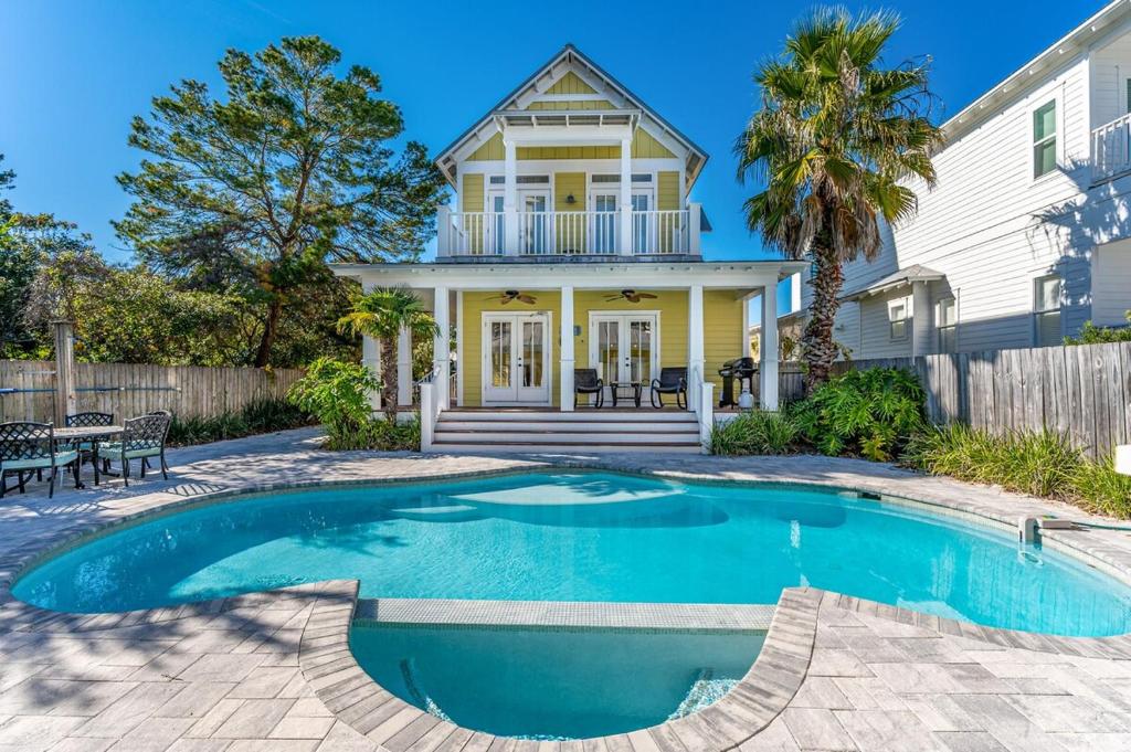 a house with a swimming pool in front of a house at Yellow Pearl Pool heat GolfCart deals Steps2Beach in Destin