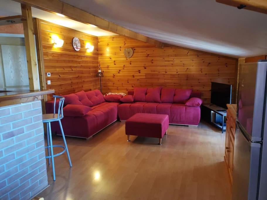 a living room with a red couch and a tv at Le charme montagnard in Barcelonnette