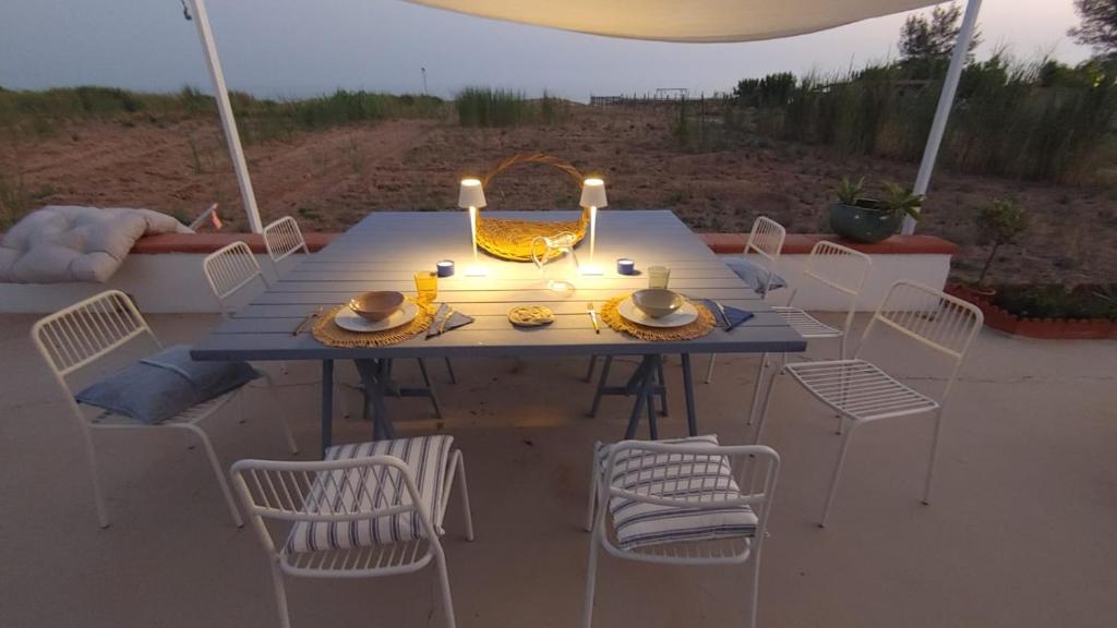 un tavolo blu con sedie bianche e candele sopra di Fin Fiori a Menfi