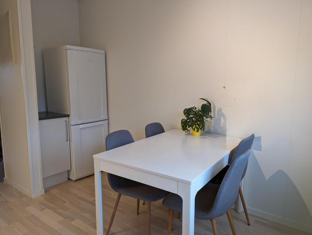 a white table with chairs and a white refrigerator at Green appartement in Sandnes