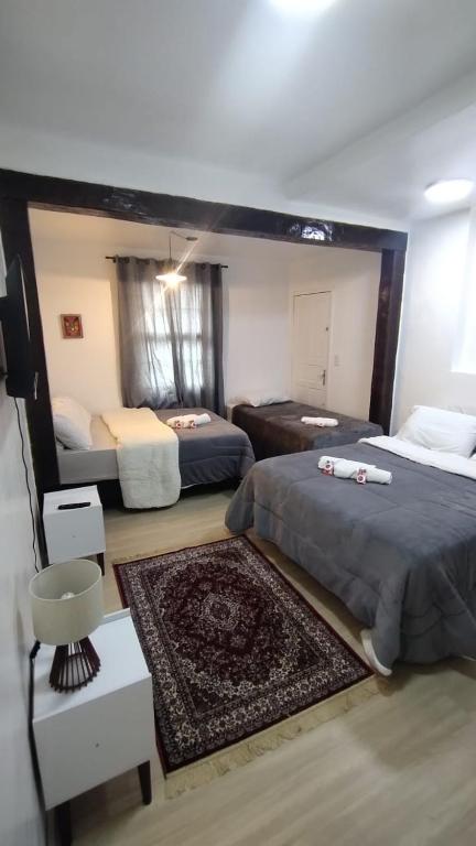 a bedroom with two beds and a rug at Suíte Master conforto e espaço vizinha do Palácio de Cristal! in Petrópolis