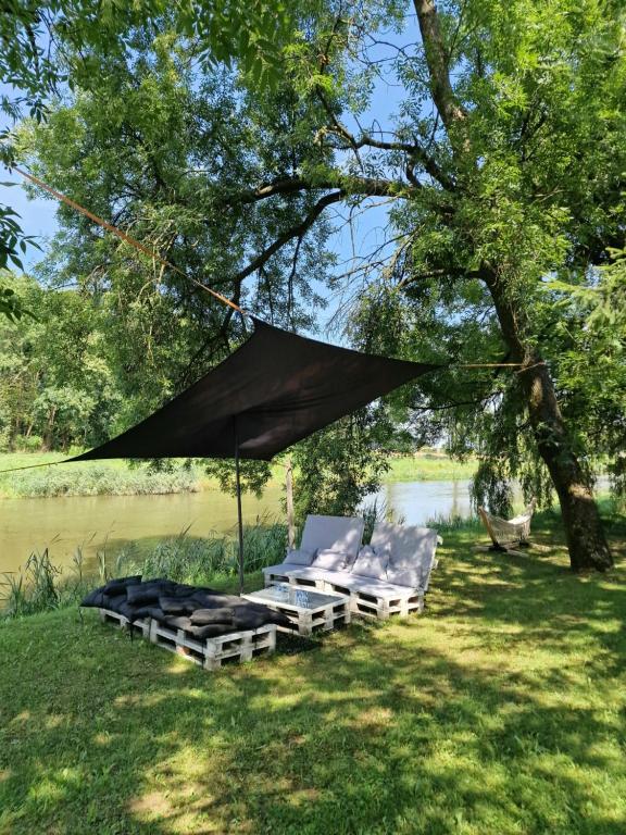 a group of chairs under a tent next to a river at Noclegi nad Wodą in Brzeźnica