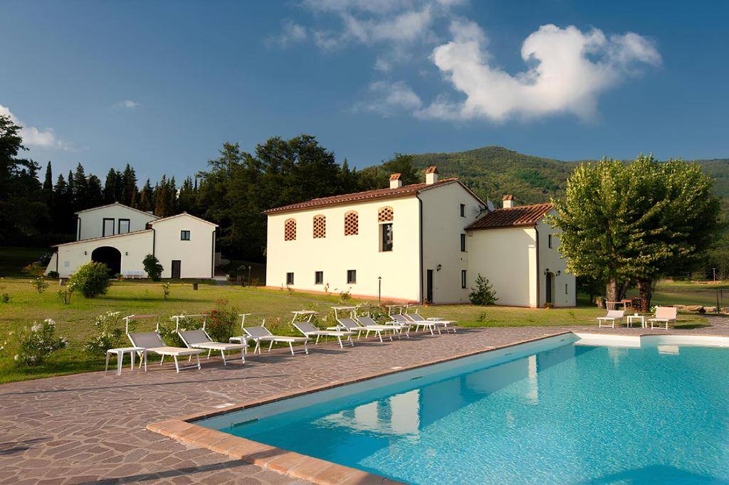 a swimming pool with chairs and a house in the background at Fattoria Javello - Agriturismo La Casaccia in Montemurlo