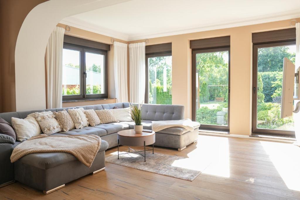 ein Wohnzimmer mit einem grauen Sofa und Fenstern in der Unterkunft Ferienhaus in Brandenburg an der Havel in Brandenburg an der Havel