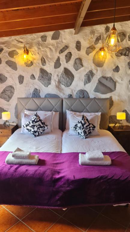 a bedroom with two beds and a stone wall at Los Cerrajones: spectacular views from the cliff in Agulo