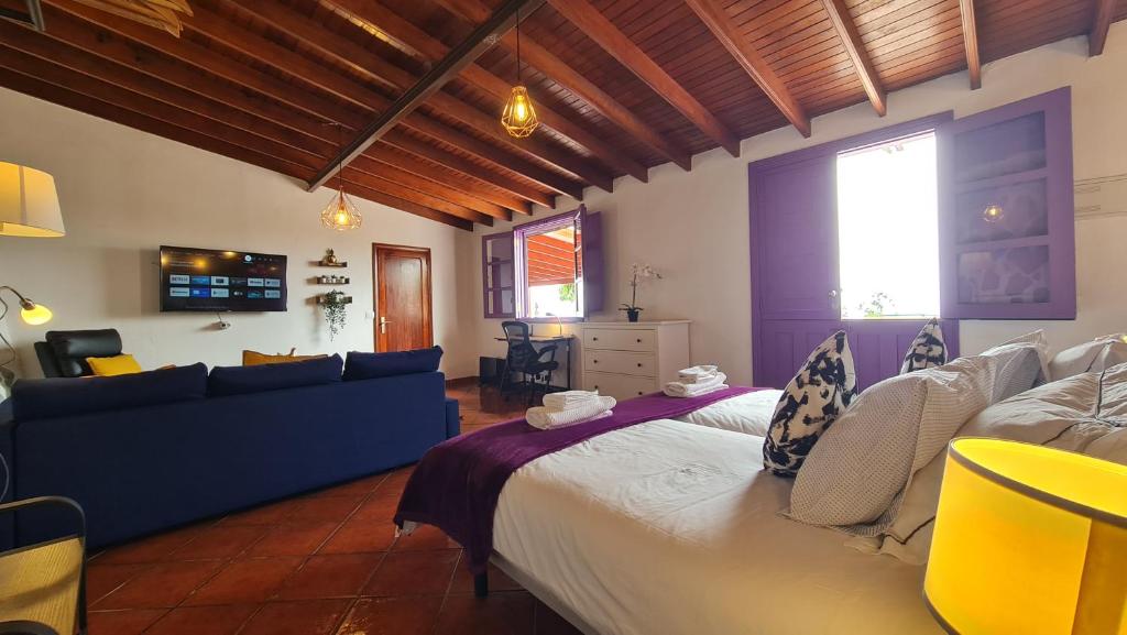 a bedroom with a large bed and a blue couch at Los Cerrajones: spectacular views from the cliff in Agulo