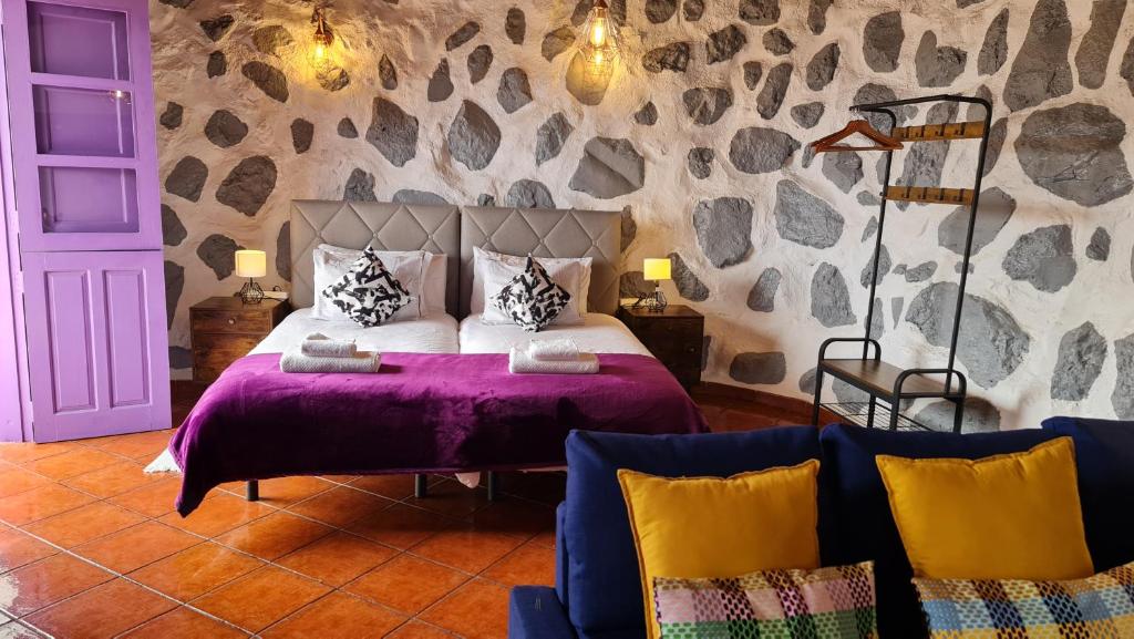 a bedroom with a bed with a purple bedspread at Los Cerrajones: spectacular views from the cliff in Agulo