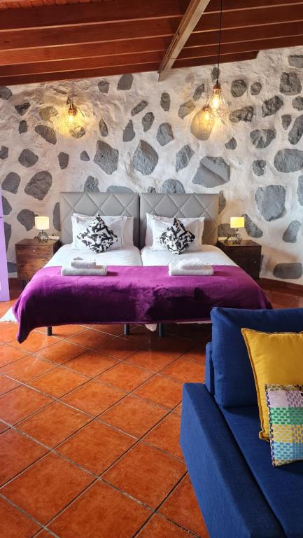 a bedroom with a bed and a stone wall at Los Cerrajones: spectacular views from the cliff in Agulo