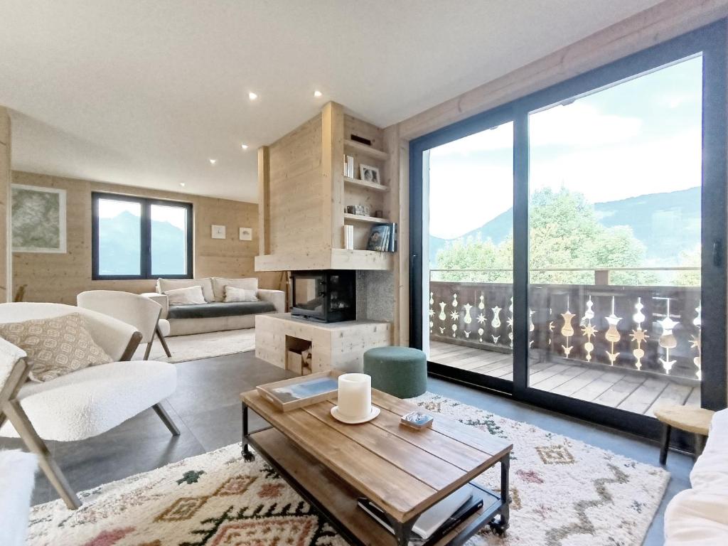 un salon avec une cheminée et une grande fenêtre dans l'établissement Chalet Le Splendide, à Saint-Gervais-les-Bains