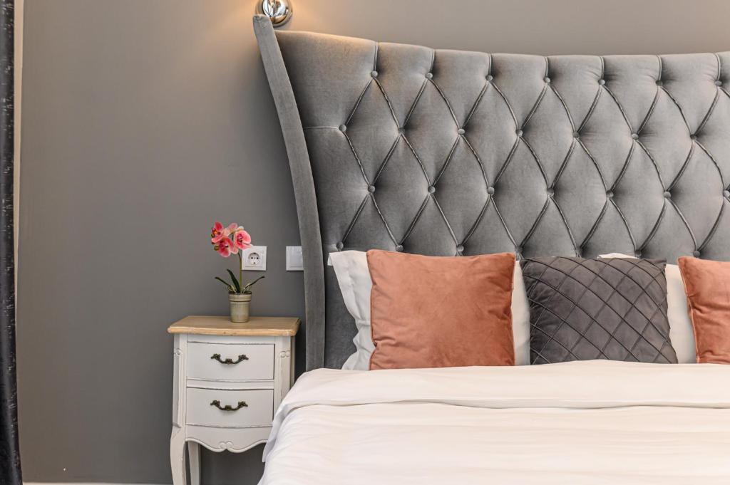 a bed with a grey padded headboard and a side table at Dallure House Boutique Brasov in Braşov
