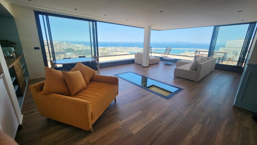 a living room with a couch and views of the ocean at Magnifique penthouse 160m2 terrasse 90m2 vue mer in Tangier