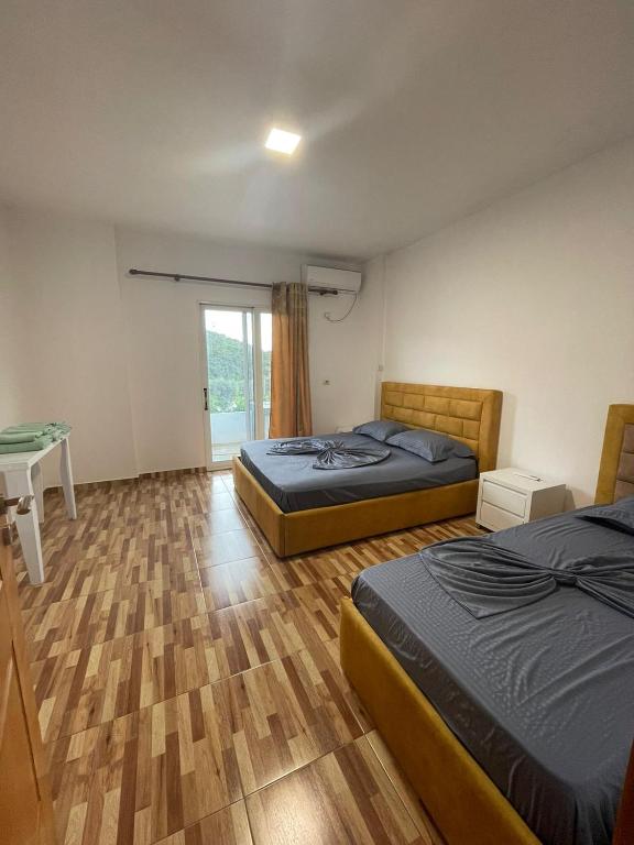 a bedroom with two beds and a desk and a window at Nikolla's apartment in Himare