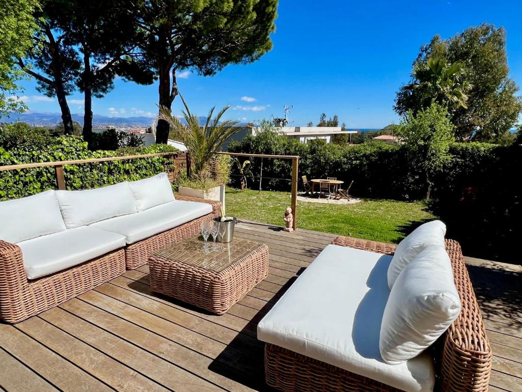 une terrasse en bois avec des meubles en osier et une table dans l'établissement Maison dans résidence avec piscine et tennis, à Antibes