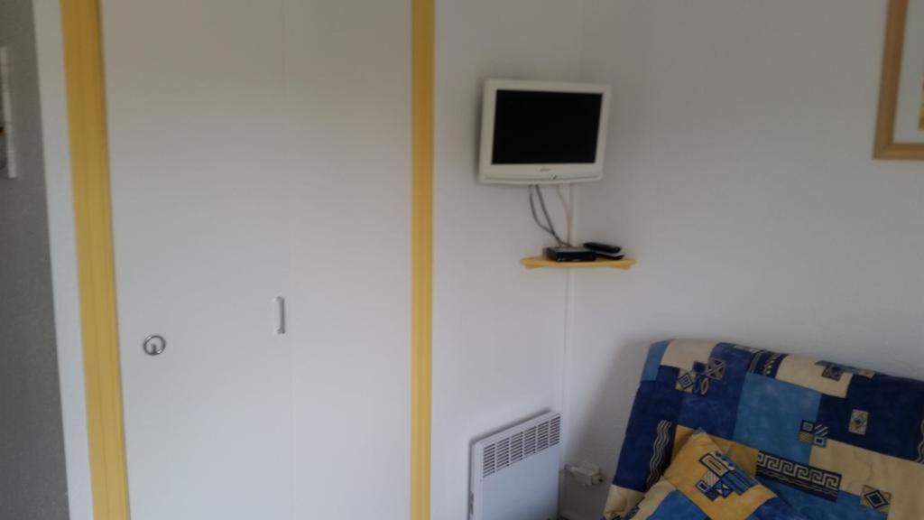 une télévision sur un mur à côté d'un lit dans l'établissement Studio Cap d’Agde centre port, au Cap d'Agde