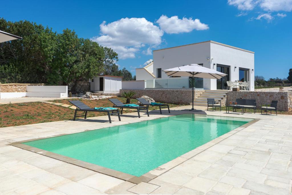 une piscine avec des chaises et un parasol ainsi qu'une maison dans l'établissement Villa Lorenbea by salentoltremare, à Castrignano del Capo