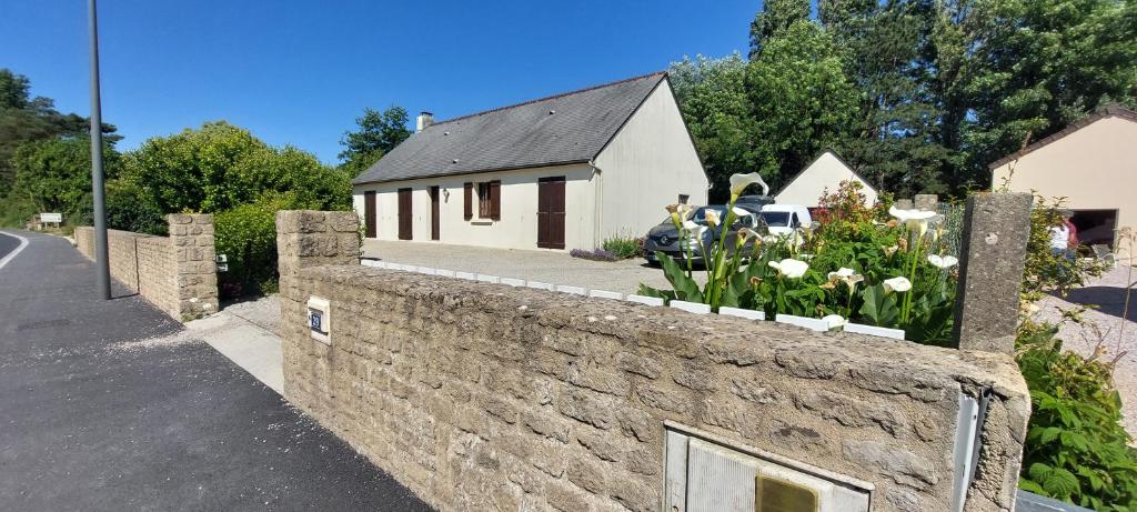 un mur de pierre avec des fleurs au sommet d'une maison dans l'établissement Ô Ptits KER - 6 à 8 personnes A proximité de la mer, à Quettehou