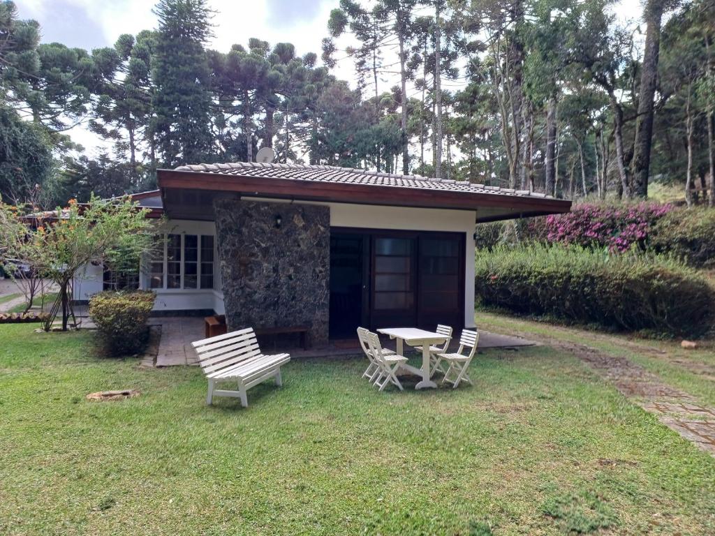 a small house with a table and chairs in the yard at Huluan Alto da Boa Vista in Campos do Jordão