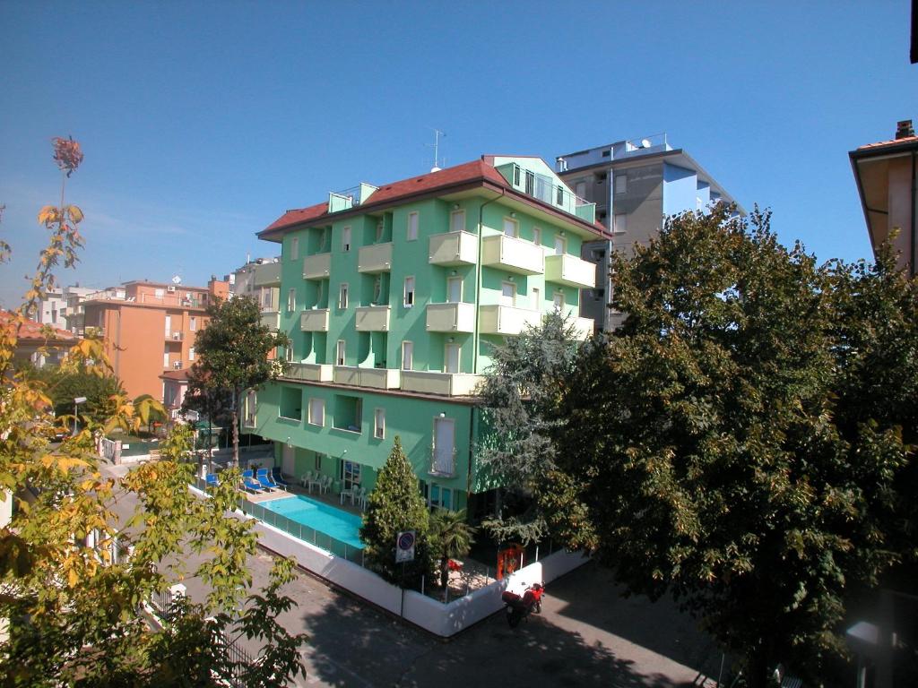 a green building with a swimming pool in a city at Residence Eurogarden in Rimini