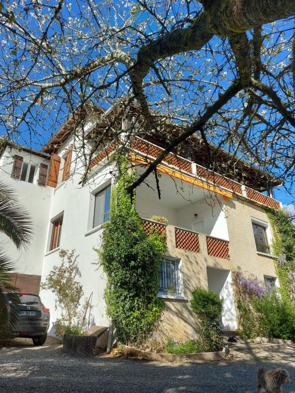 une maison blanche avec une voiture garée devant elle dans l'établissement La Tuilerie, à Barcelonne-du-Gers