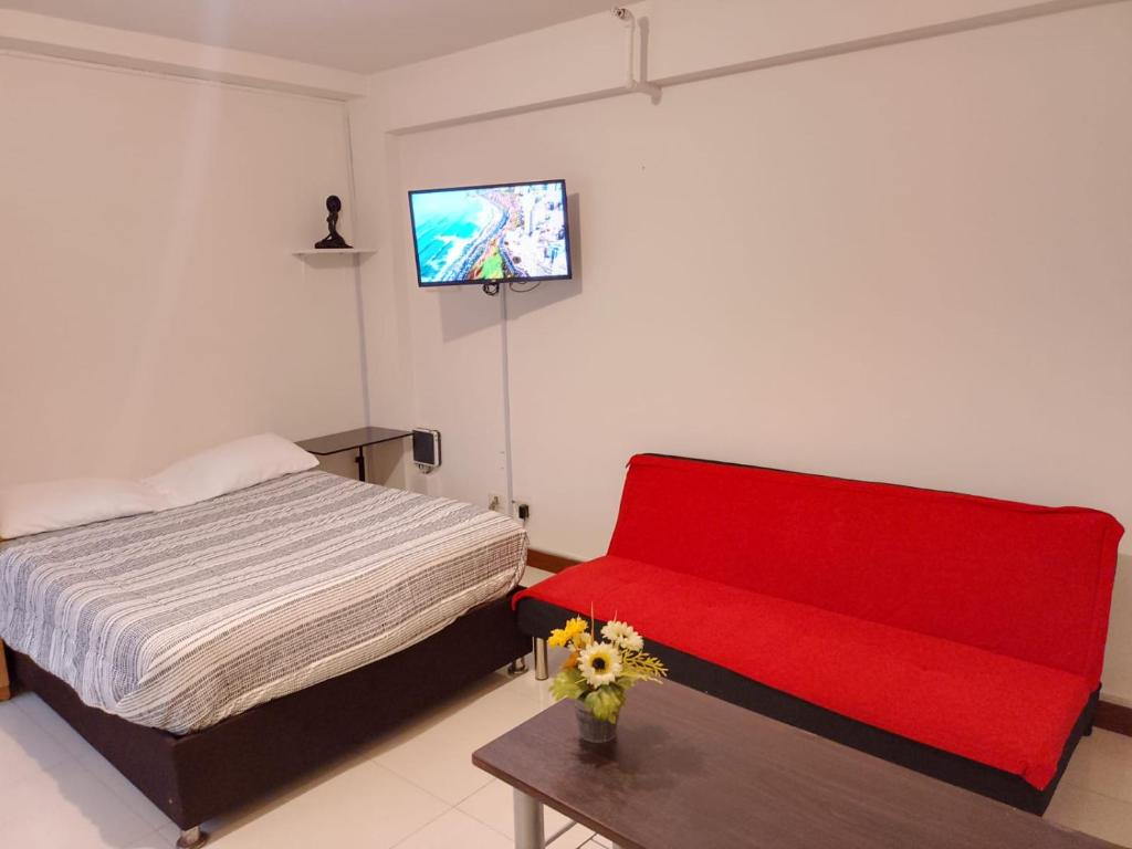a bedroom with a red couch and a tv on the wall at Departamentos Céntricos en Lima in Lima