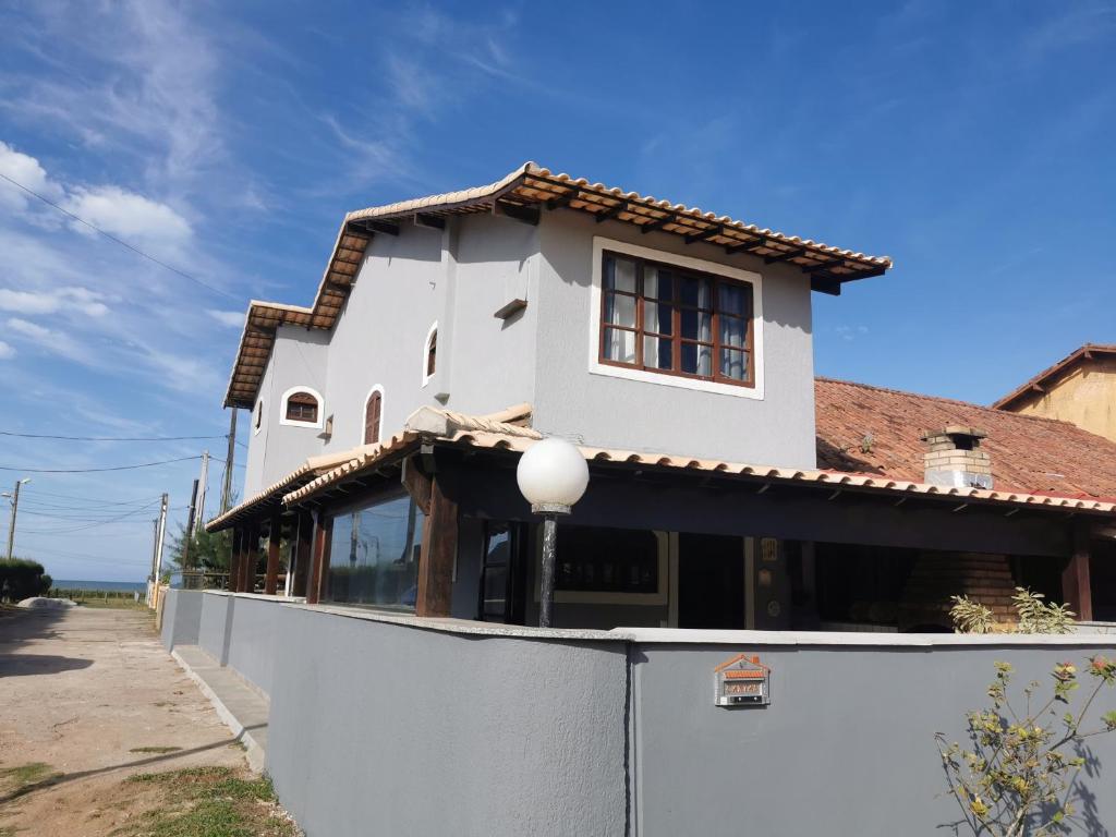 a white house with a fence in front of it at Casa Azul na Praia do Verão Vermelho in Cabo Frio