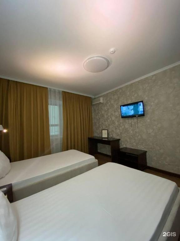 a hotel room with two beds and a flat screen tv at Diar in Atyrau