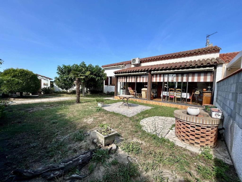 une maison avec une cour avec un foyer à l'intérieur dans l'établissement Villa familiale climatisée avec jardin, proche plage, parking, Wifi et barbecue - Saint-Cyprien - FR-1-225D-218, à Saint-Cyprien