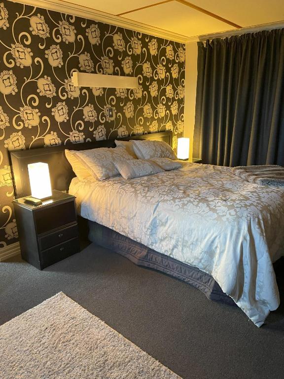 a bedroom with a bed and two lights on a wall at Down South Cottage in Invercargill