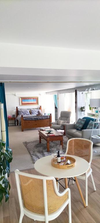 a living room with a table and chairs and a bed at The Glade, peace among the trees on the river in Urunga