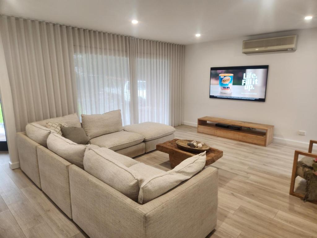 a living room with a couch and a tv at Mornington Holiday House Four bedrooms in Mornington