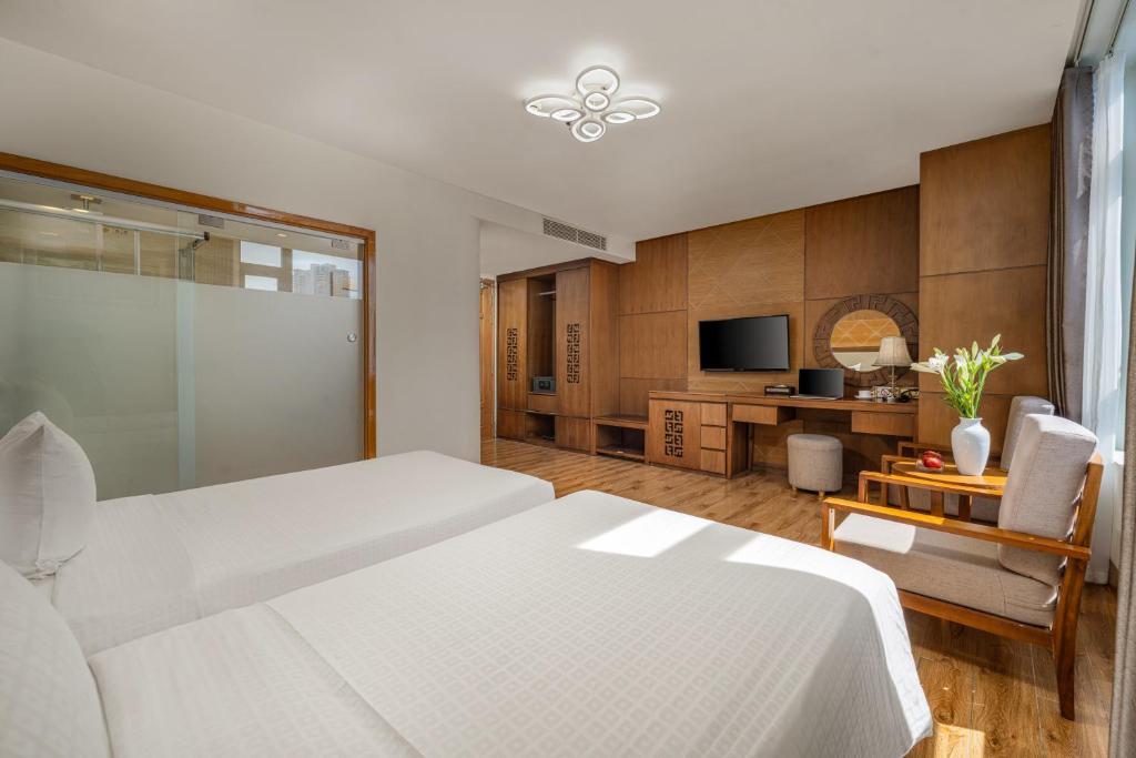 A double bedroom with a TV console, lounge chair and frosted-glass bathroom wall.