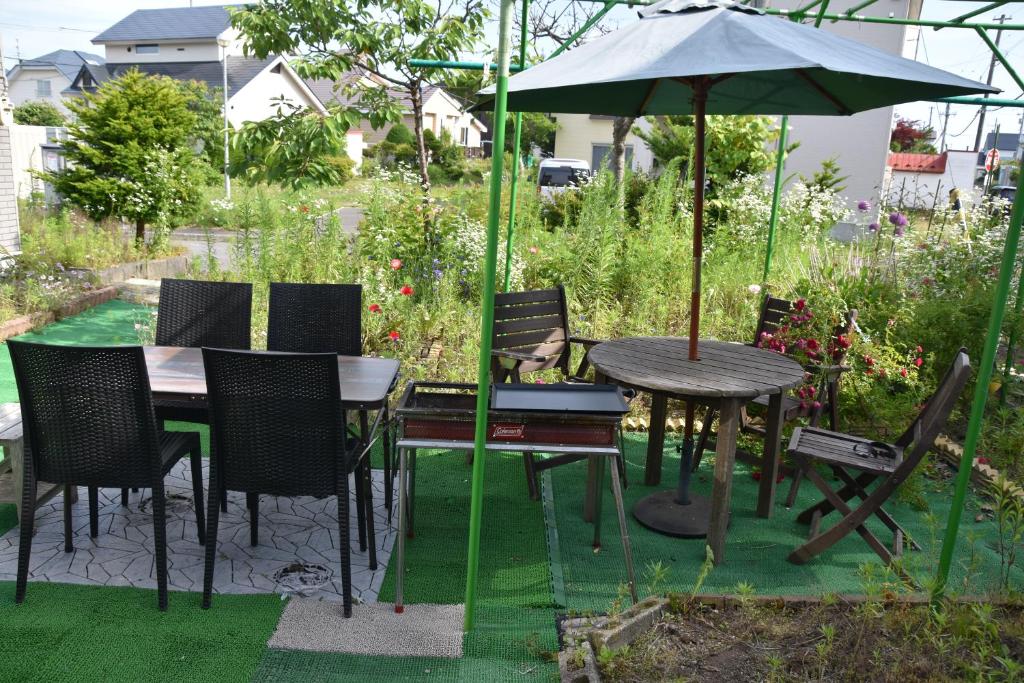 a table and chairs with an umbrella in a garden at LY inn Chitoseairport in Chitose