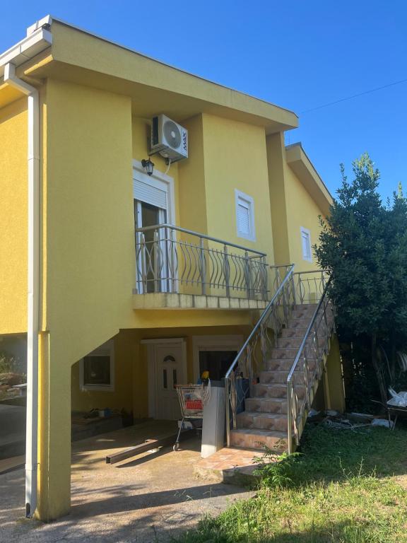 a yellow house with a balcony and stairs at SNG Apartmani in Brca